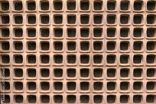 Symmetrical geometric breeze block wall pattern with repeating square lattice structure and warm terracotta tone