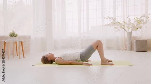 Side view of short haired woman doing bridge exercise on mat at home