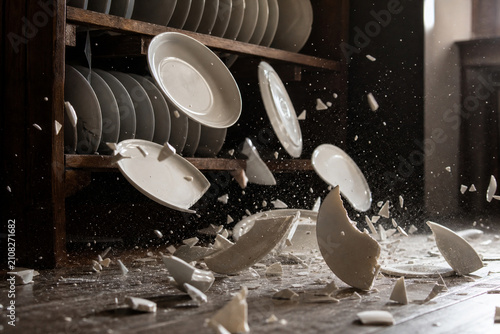 White porcelain plates shattering on floor, frozen motion, dramatic lighting.
