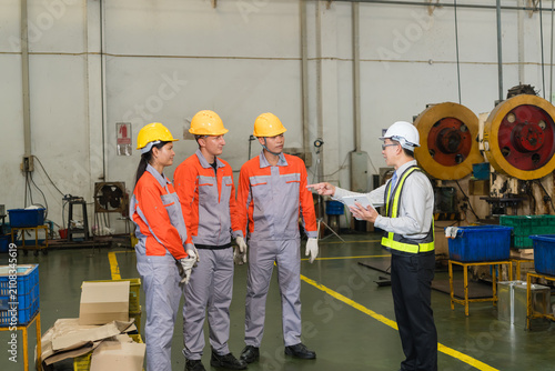Cuadro en lienzo Engineer pointing while briefing coverall clad workers beside heavy duty stampin
