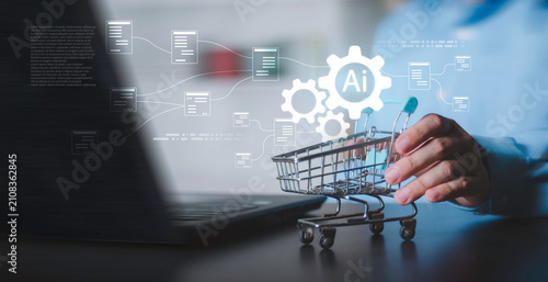 Concept of automated e-commerce, smart retail technology, digital supply chain and logistics workflow on laptop desk. Hand holding mini shopping cart with glowing AI gears and document icons.
