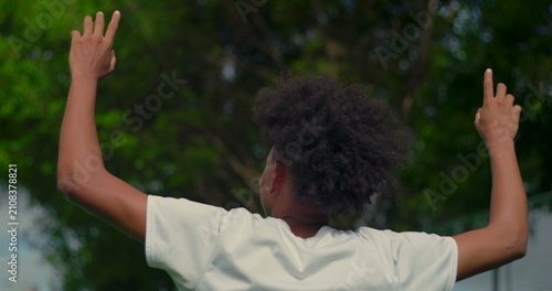 Obraz na plátně Young African American man raising hands toward the sky from behind, expressing