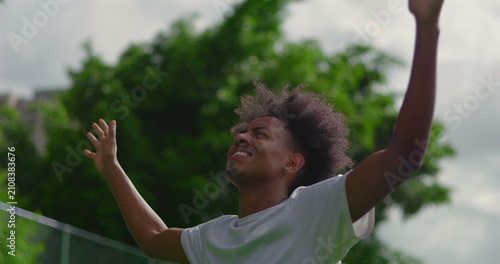 Obraz na plátně Young African American man raising arms toward sky with open hands, expressing g