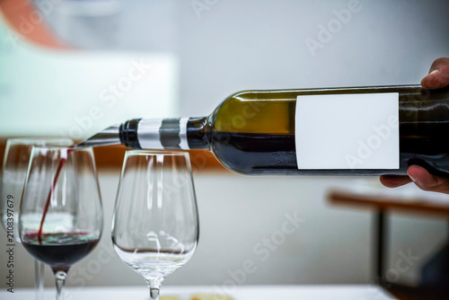 Pouring Red Wine From Bottle With Blank White Label Into Stemmed Glass