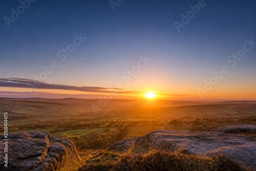 Golden rays of dawn breaking over the horizon into a deep blue pre-dawn sky.