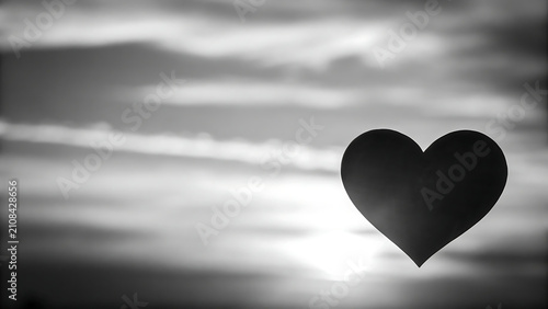 Silhouette of heart shape on water at sunset. Minimalist love symbol floating on blurred ocean waves in monochrome.
