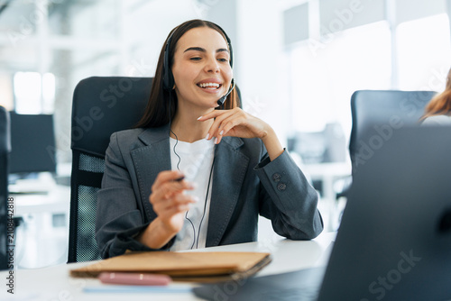 Fotografie Female call center agent wearing headset providing customer service