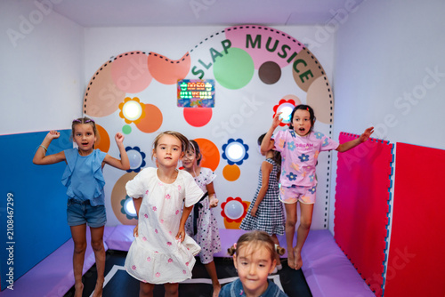 Slika na platnu Young girls enjoy an active playtime, jumping and laughing inside an indoor chil