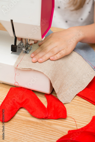 Close-up of a preteen girl's hands sewing fabric on a sewing machine, highlighting creativity, crafting skills, DIY hobbies and learning practical skills at home.