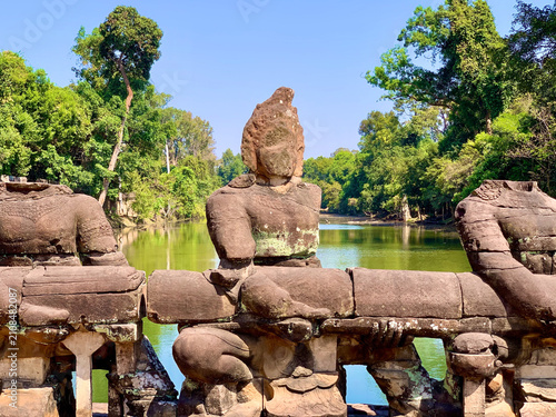Принти на полотні Neak Pean, Cambodia - February 21, 2020: Wild Monkey Resting on a Naga Sculpture