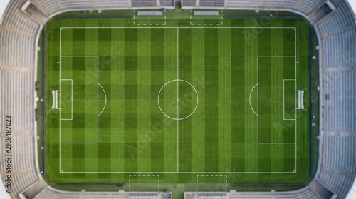 Aerial view of a vibrant soccer stadium with green pitch. Wide-angle shot of a professional sports arena during daytime, showcasing the lush grass...