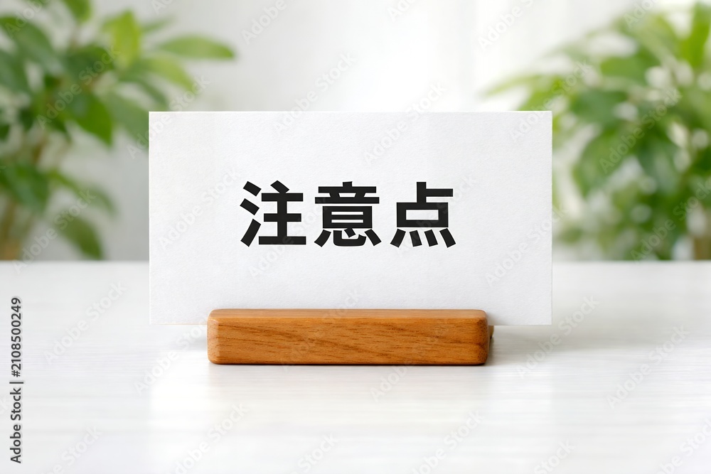 Obraz premium 「注意点」と書かれた白いカードが木製スタンドに立つビジネスシーン