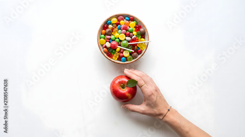 Hand Choosing Apple Over Candy Bowl Healthy Snack Concept
