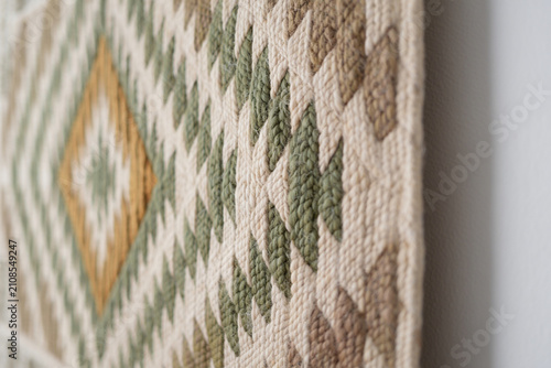 Geometric tapestry with diamond shapes in green and beige woven detail