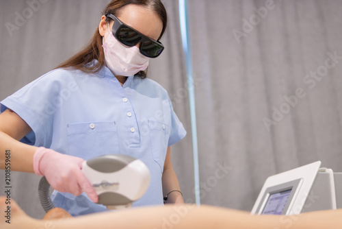 Cuadro en lienzo Woman receiving modern laser hair removal treatment from a beautician in medical