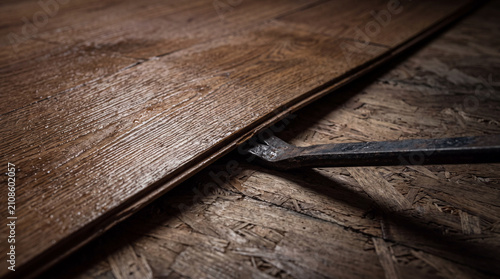 A vintage metal crowbar prying open a rough wooden board.