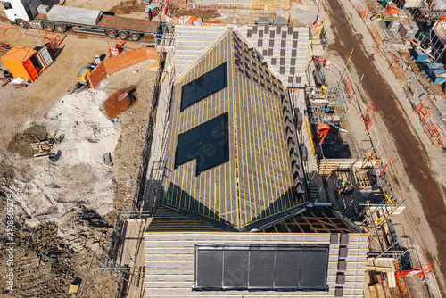 Construction of a new building with solar panels on the roof seen from above in an urban area