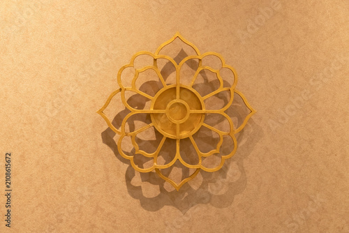 An elegant golden lotus flower mandala wall ornament mounted on a warm-toned textured wall, featuring soft shadows and a luxurious aesthetic, ideal for interior design and background concepts.