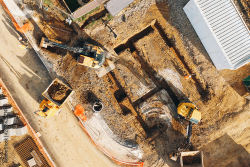 Construction site showing excavation work in progress during daylight hours with machinery and earth moving vehicles