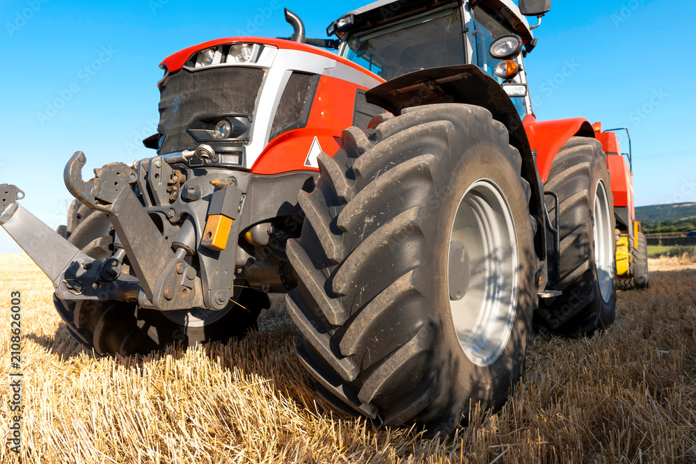 Obraz premium Farm tractor working in a field during daytime while preparing soil for planting