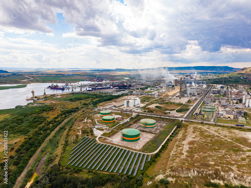 фотографія Industrial area near a river with storage tanks and solar panels under a cloudy