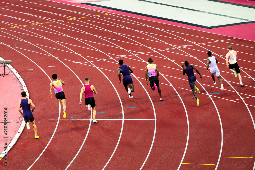 Fototapeta premium Sprinters racing on an athletics track. Muscular world-class male athletes compete in a professional 200 m sprint race. Illustrative photo of sprinting and track and field.