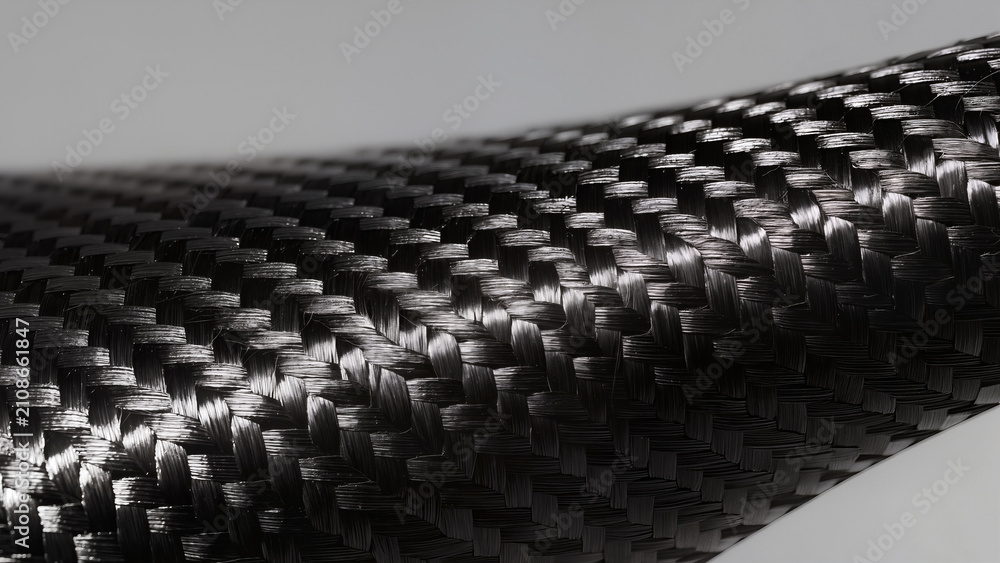 Fototapeta premium Macro photography of black carbon fiber texture with woven composite pattern and light reflection
