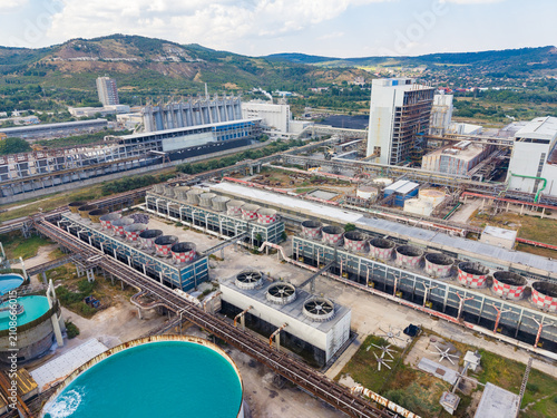 Fotografie Industrial site with buildings, water tanks, and machinery in a hilly area on a