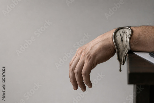 Melting wristwatch hangs over a relaxed hand. Space for text.