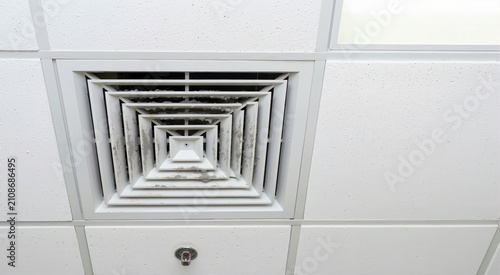 Dirty return air grille covered in thick dust on a drop ceiling. HVAC ventilation system requiring maintenance and cleaning