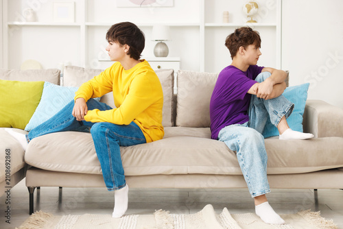 Fotografía Resentful teenage brothers sitting on sofa at home