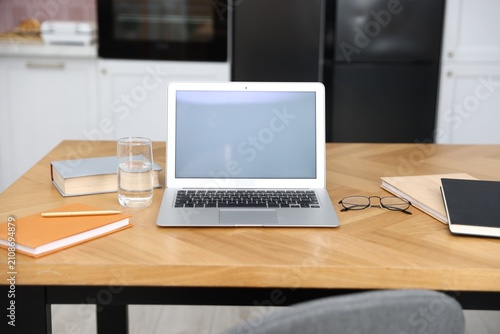 Comfortable workplace with laptop on wooden table indoors