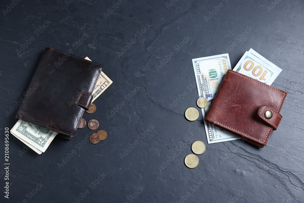 Naklejka premium Contrast between poor and rich. Leather wallet with large bills and old one with small bills and coins on dark textured table, flat lay. Space for text