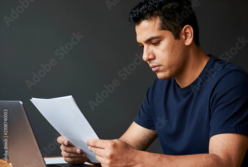 Young hispanic man reading ...