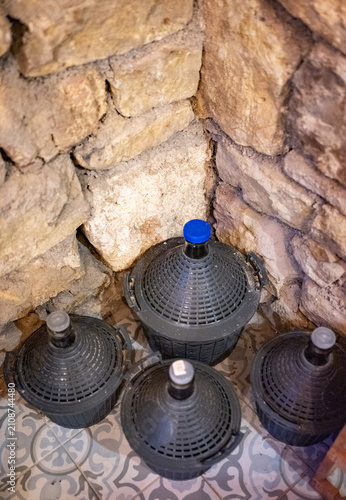 Bild auf Leinwand A high-angle view of four large glass demijohn or carboy bottles protected by da