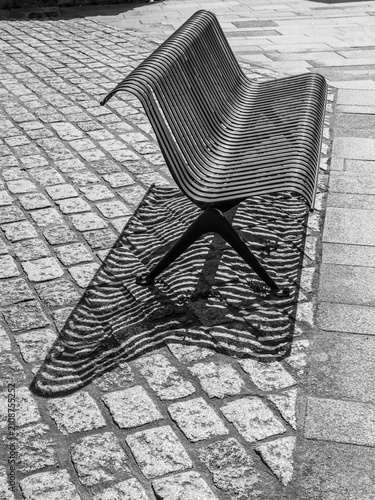 Konstfotografi moderne Parkbank in einer Fußgängerzone wirft Schatten in Wellenform