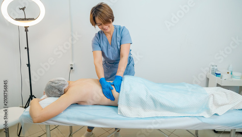 Fotografie Masseuse doing a therapeutic relaxing back massage to a girl in the spa