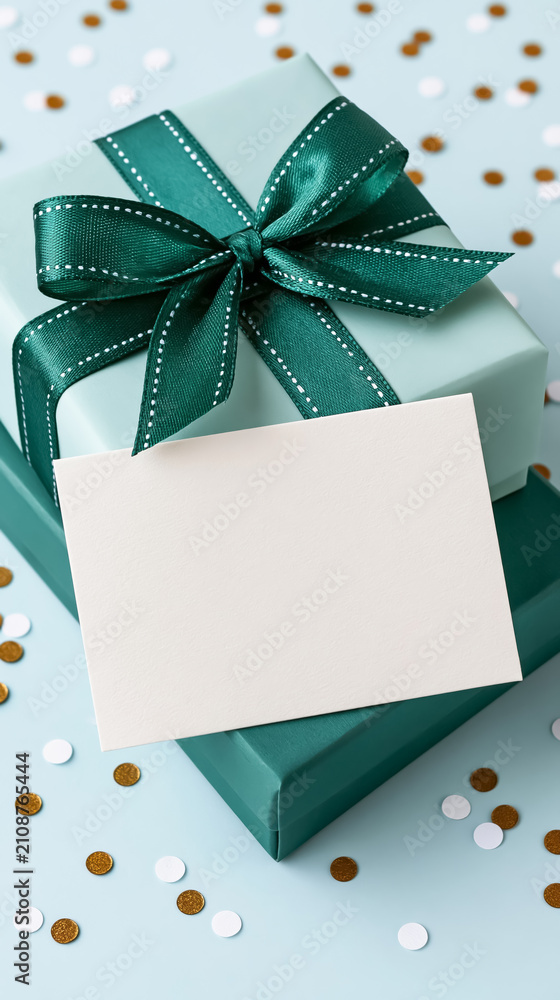 Obraz premium Teal wrapped gift box with bow and blank card on confetti background