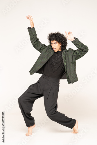 Obraz na plátně Young man with curly afro hair, intense gaze and bright white smile, wearing tex