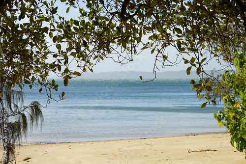Foto Tropical beach and turquoise sea framed by overhanging tree branches