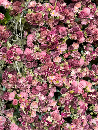 Eastleigh Hampshire UK. 18.07.2026. A dense wall of artificial flowers in shades of pink and deep purple, interspersed with delicate ferns