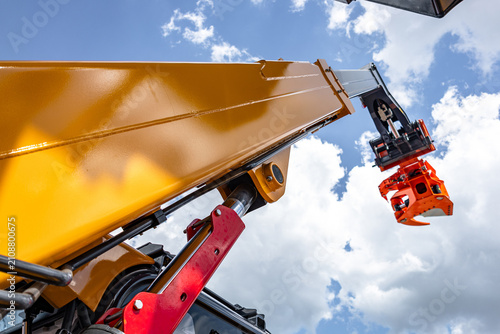 Telehandler telescopic boom arm with hydraulic lift cylinder. Modern construction machinery yellow crane mechanism section against sky background with industrial heavy duty vehicle details.