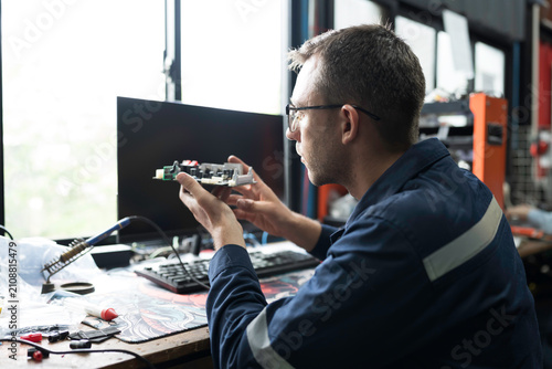 Obraz na płótnie Male electrician engineer using soldering iron repairing electronic printed circuit board