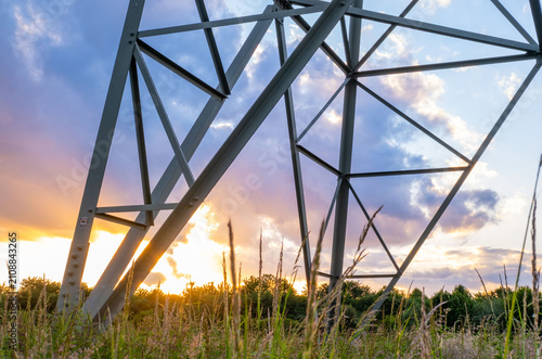 High voltage transmission power lines and electricity pylons silhouette against sunset sky with soft clouds, Sustainable energy infrastructure and power supply concept, industrial scenery meets nature