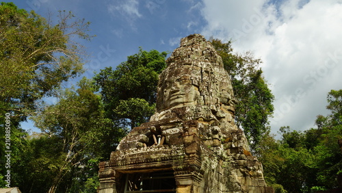Foto Ancient stone tower with giant carved face surrounded by green jungle