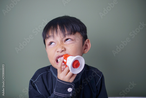 Obraz na plátne Funny young child making a silly facial expression while pretending to speak through a toy megaphone