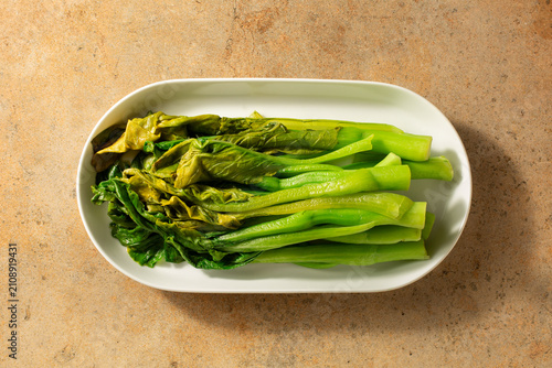 A top down view of a plate of blanched yu choi.