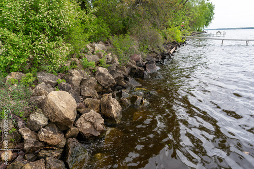 Riprap rock barrier along a green lake shoreline
