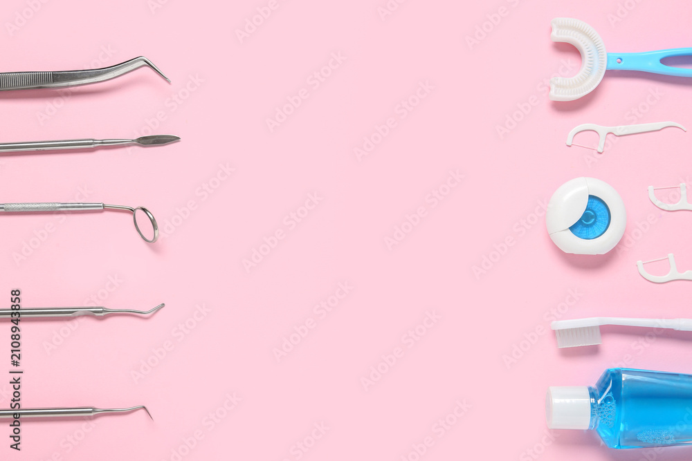Fototapeta premium Dental instruments and oral hygiene products arranged on a pink background for dentistry and health care concepts, the left side displays various stainless steel dental tools including a mirror