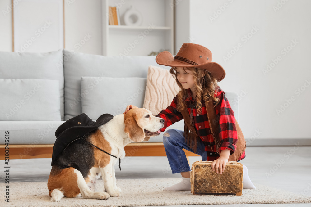 Obraz premium Cute little girl and Beagle dog in cowboy hats with book at home